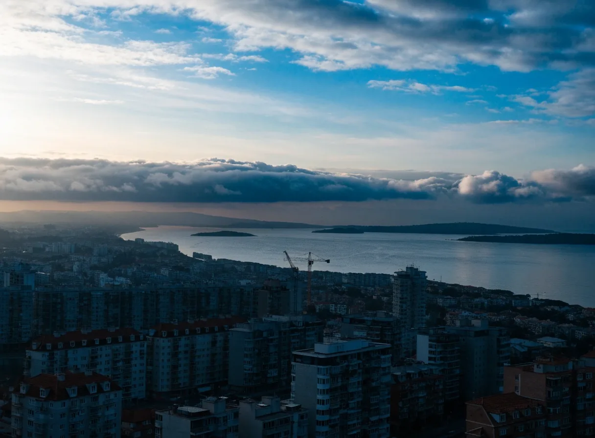 Ciudad costera española a primera hora, con edificios densos y un frente de nubes detrás